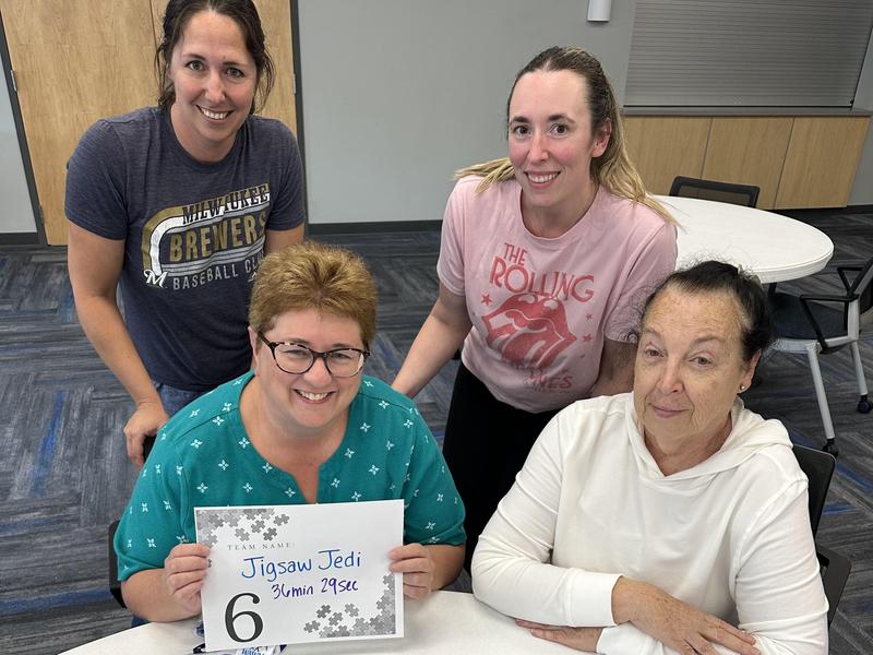 Winning team of 4 women posing with their completed puzzle for Puzzle Palooza