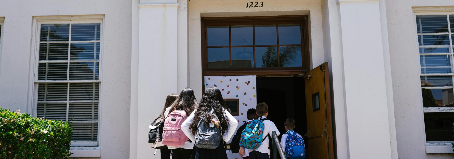 a group of students walking into the front door of the school building