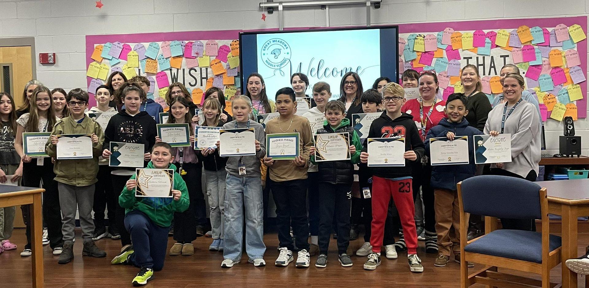 Group of students holding certificates with colorful decorations in the background.