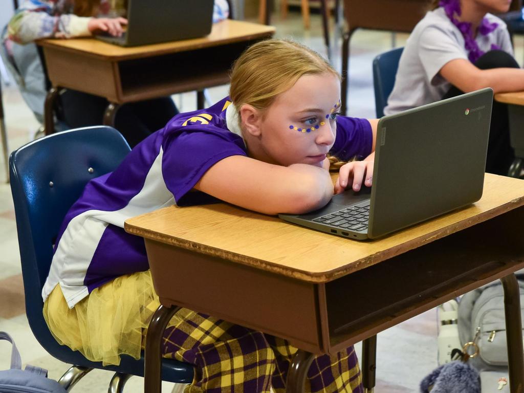 A student wearing spirited Pirate gear looking at her desk looking at her Chrombook screen.