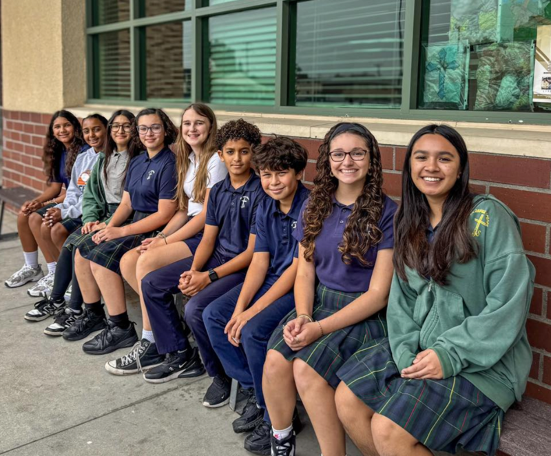 Nine St. James Student Council Members sit on a bench smiling