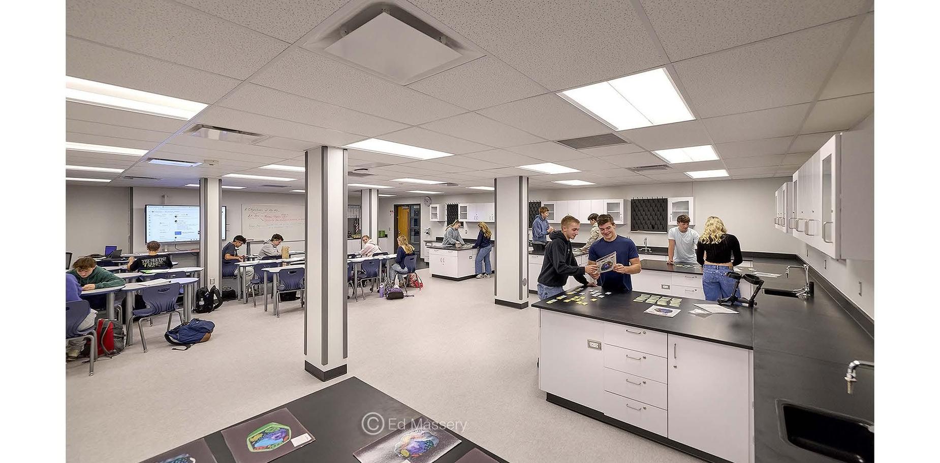 A science lab filled with students working at tables, experimenting and collaborating.