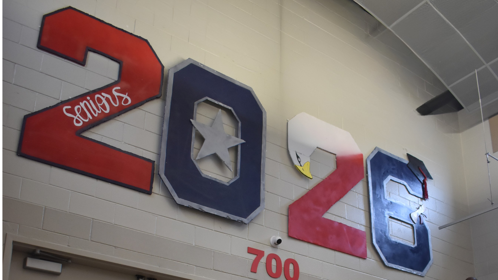 Large '2028' sign with a star and a decorative eagle, hanging on a wall.