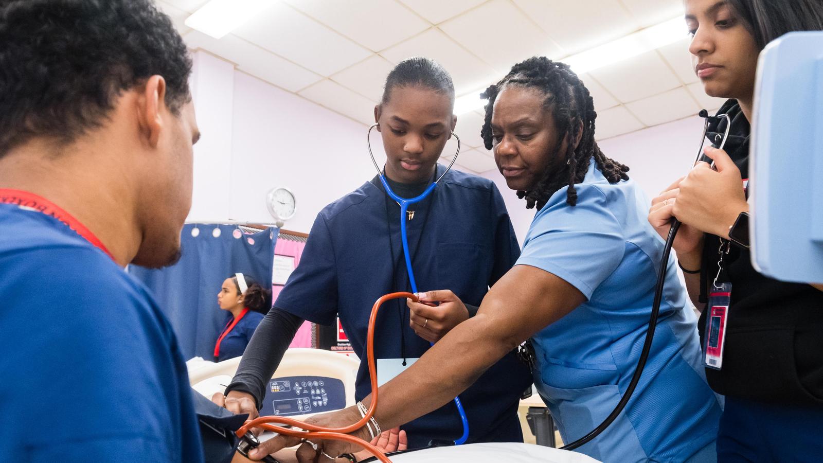 Students and a teacher in scrubs in the health assisting program at Brockton High