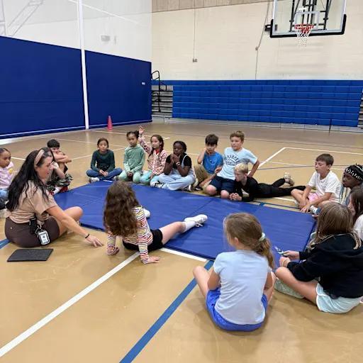 Students and teacher gathered around a matt in gym class