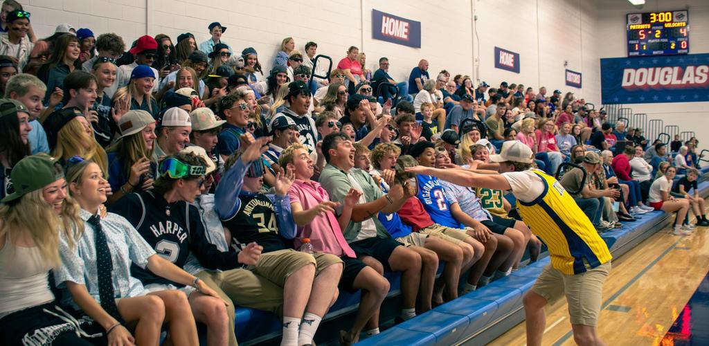 Patriot crowd of enthusiastic students cheering at a volleyball game.