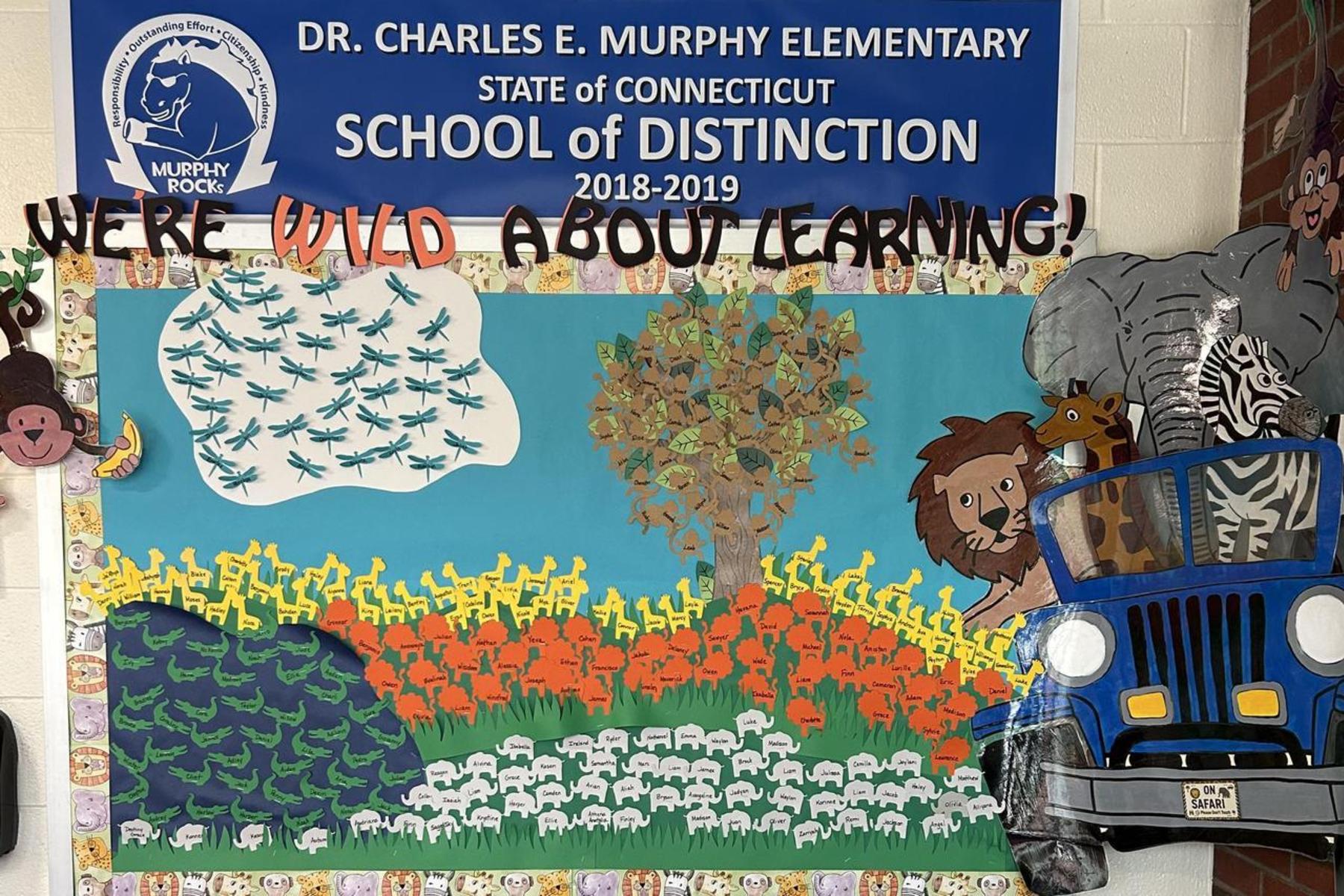 A colorful school display featuring animals, trees, and a banner promoting learning.