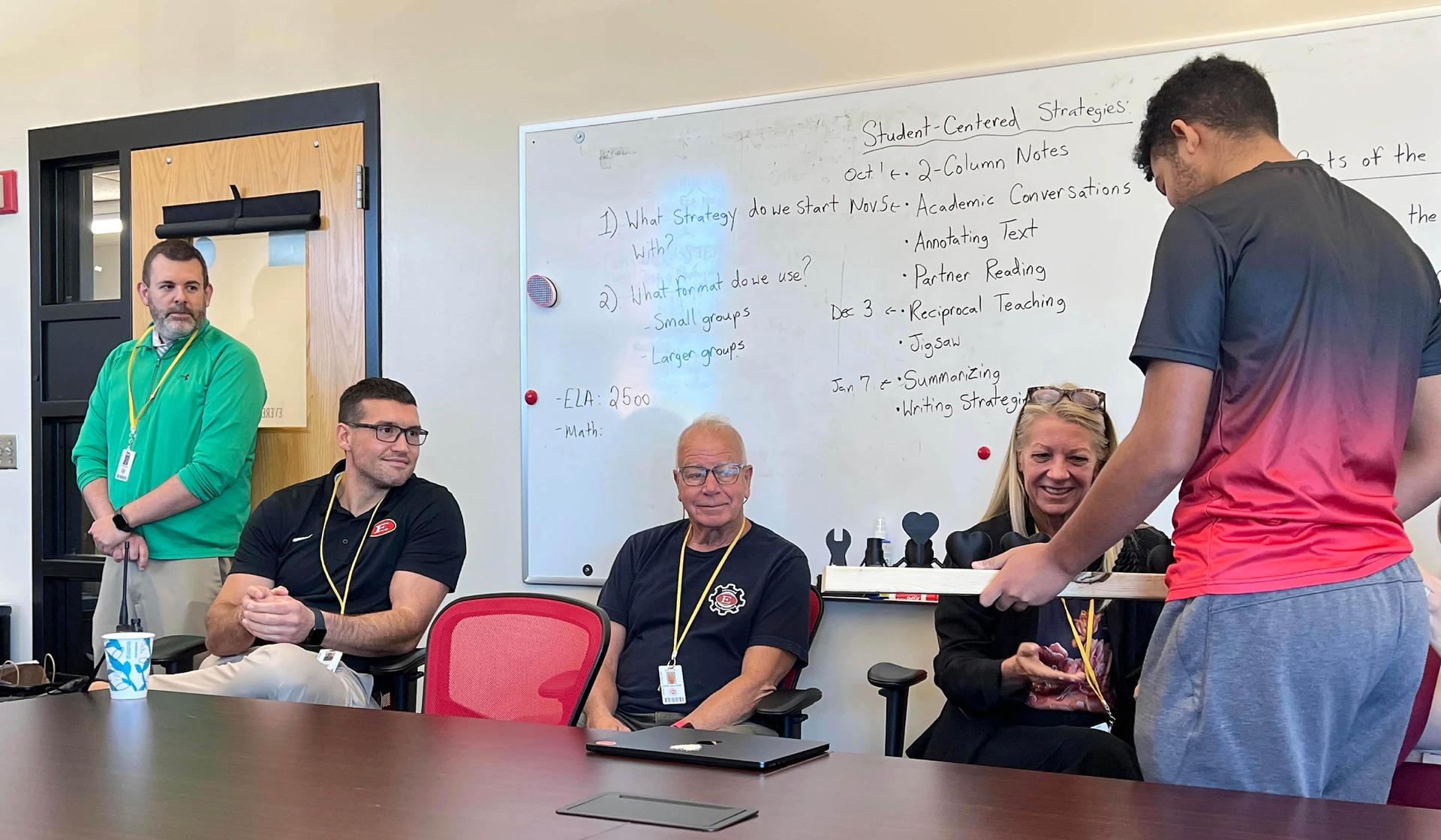 Students engaged in a workshop discussion with notes and teaching materials on a whiteboard.