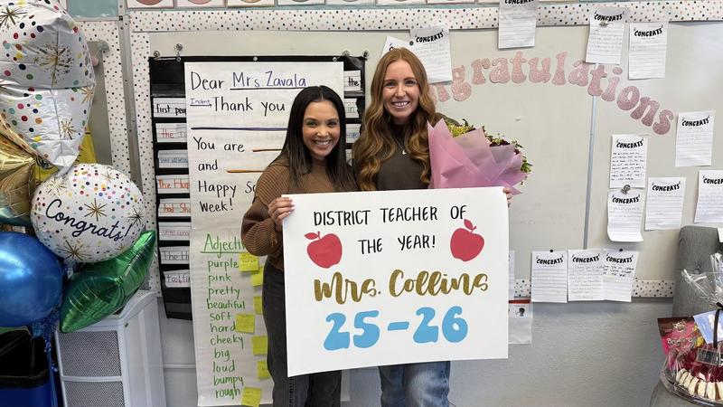 photo of courtney collins and erika lopez holding up a sign that reads Teacher of the Year