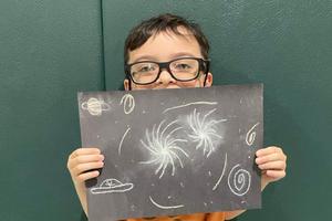 First-grader Logan Kester holds his finished galaxy artwork