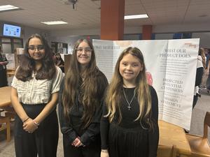 Smiling students stand with school projects