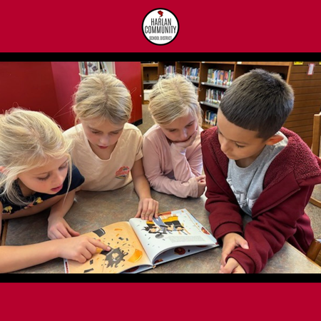 Four Students Reading Around A Book.