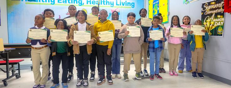 Group of students holding certificates in a classroom setting.
