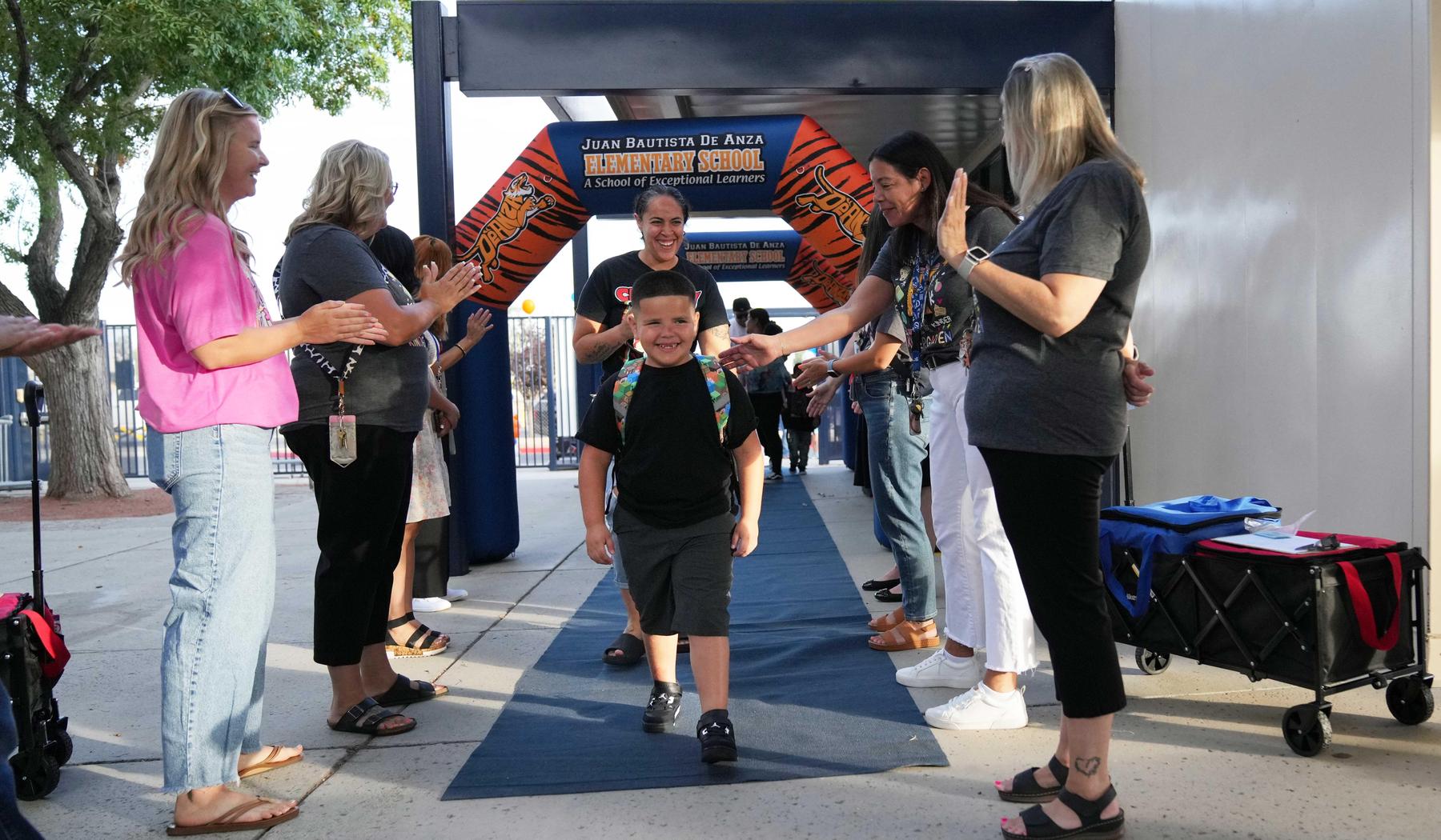 boy walking through inflatable arch with staff cheering