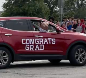 A maroon SUV has "Congrats  Grad" in lettering on the side