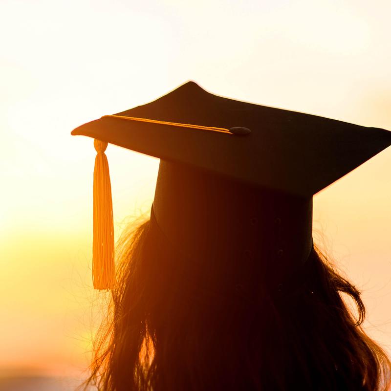 Silhouette of a graduate wearing a cap at sunset.