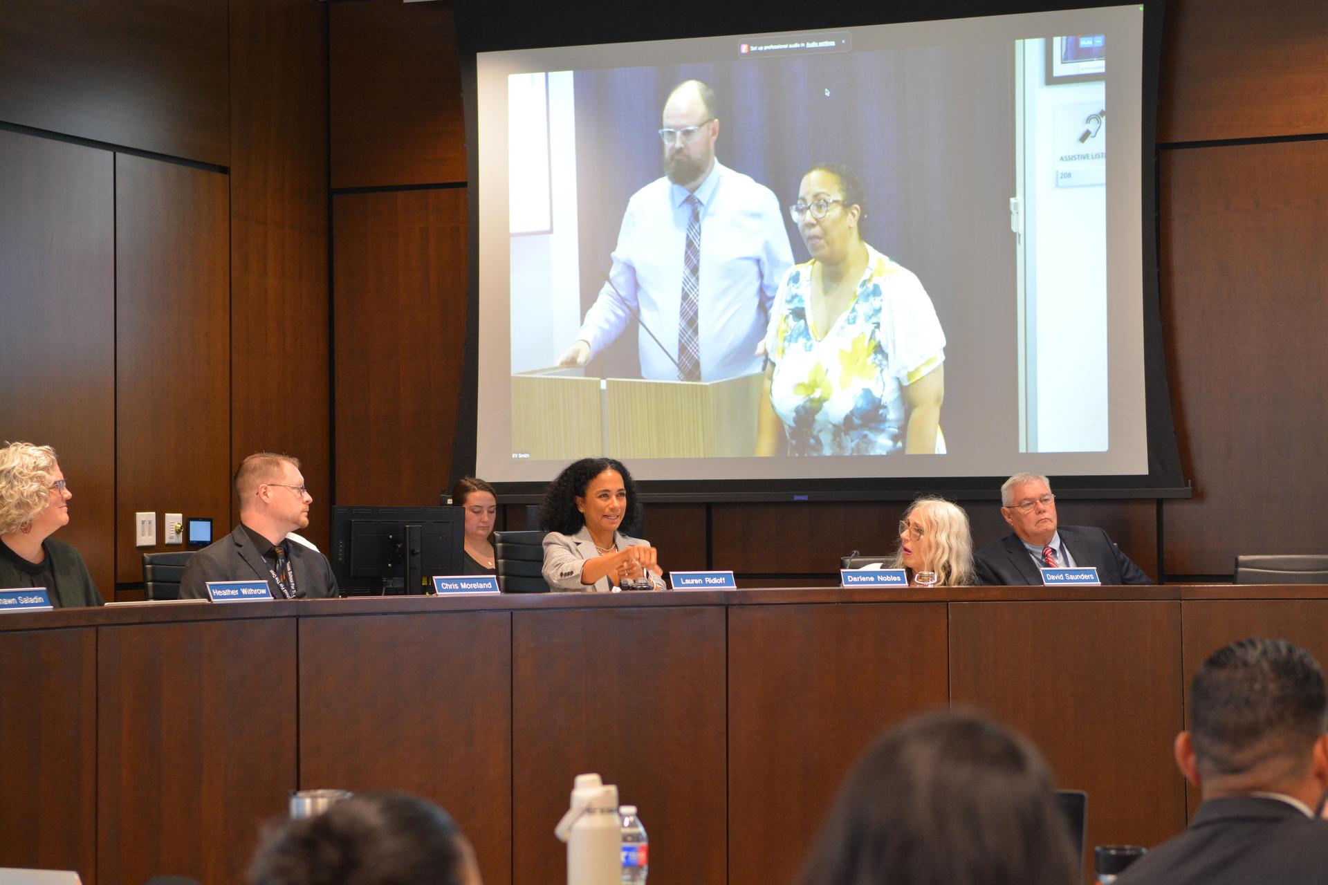 Board listens to presenters at podium.