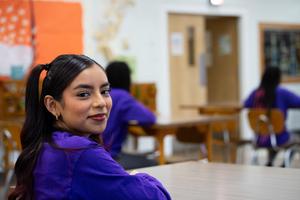 Student sitting at desk smiling at camera