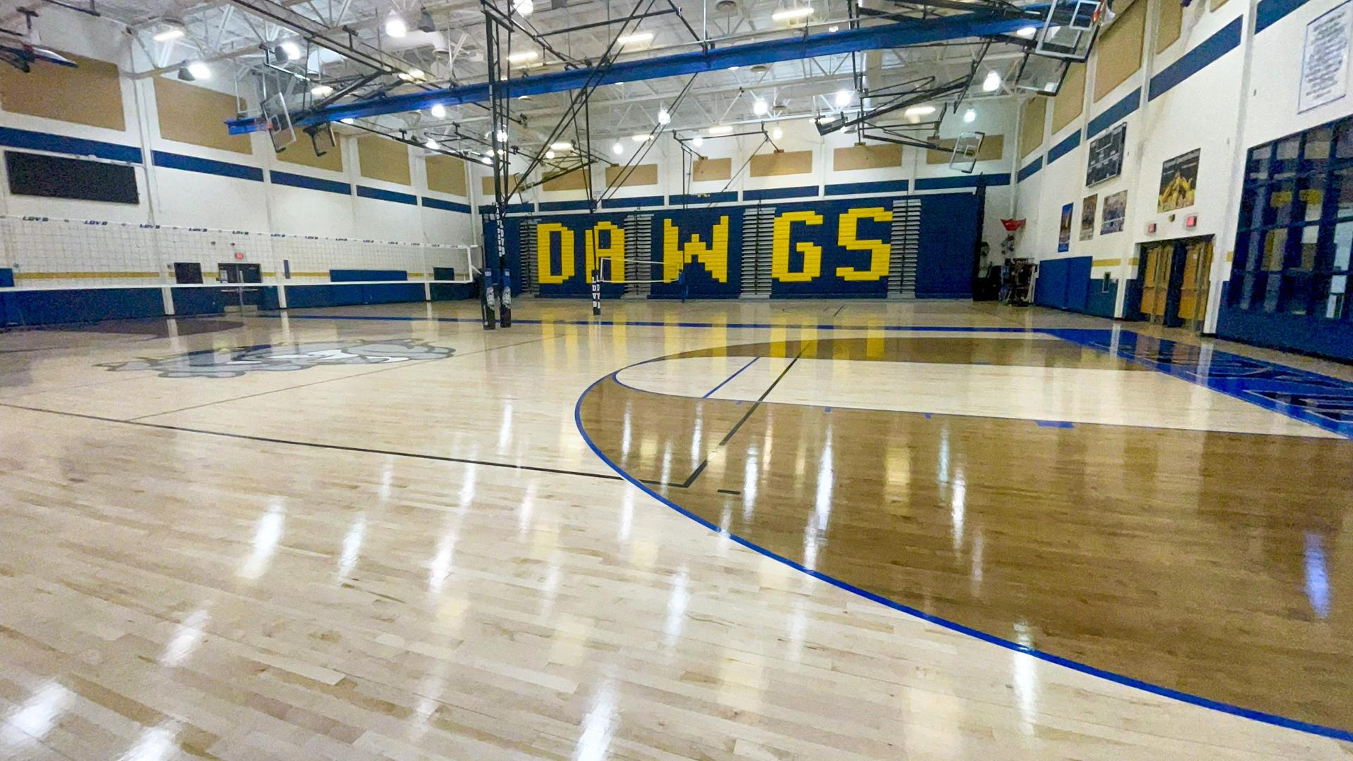 Gymnasium with polished wood floors and a yellow 'DAWGS' wall mural.