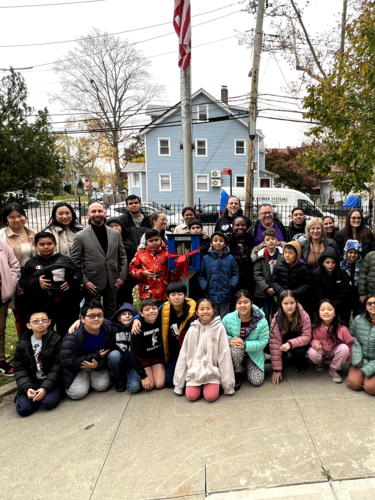  children and adults gathered around a little library