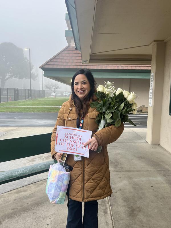counselor Dulce Ruiz holding certificate and flowers