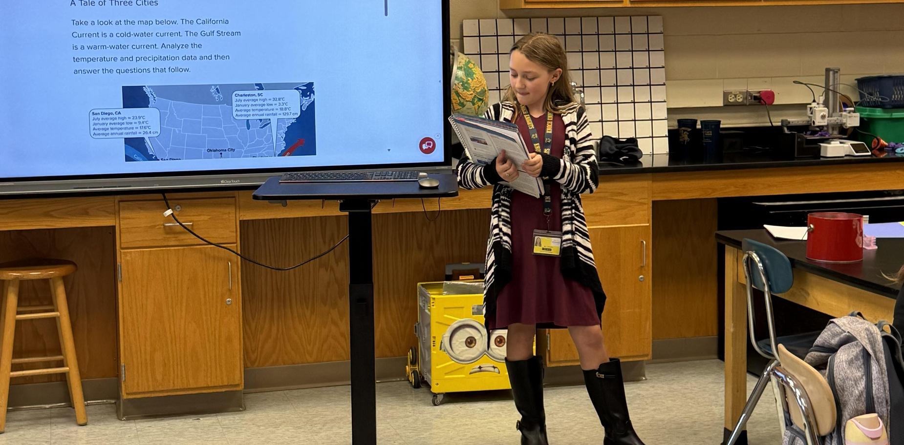 A girl presenting in a classroom with a map on a screen.