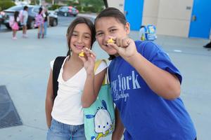 two students holding miniature ducks in front of a school