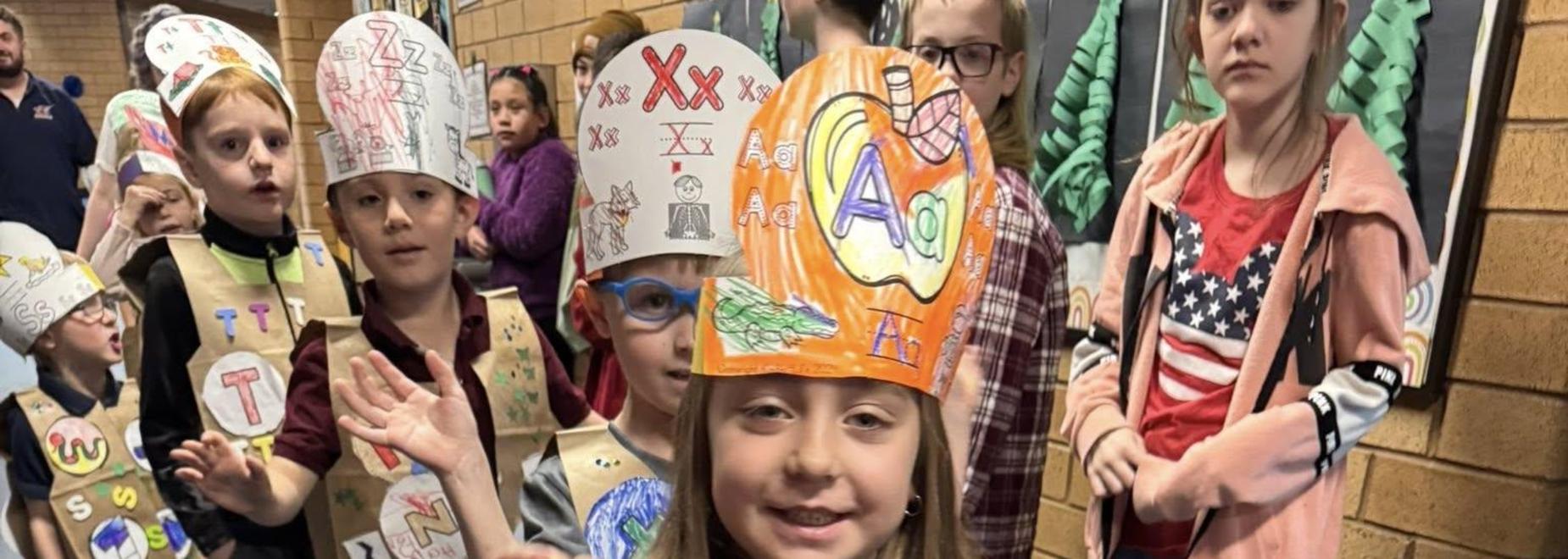 Child wearing a decorated vest with colorful drawings in a school hallway.