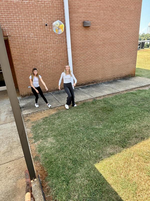 Two girls try to kick the ball up the hill