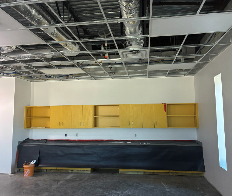 Interior of a room with yellow cabinets installed and a covered countertop.
