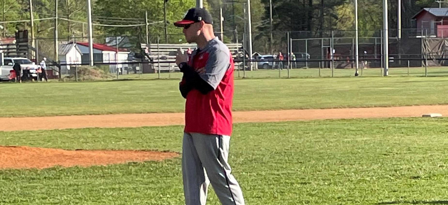 A baseball coach stands on a field.