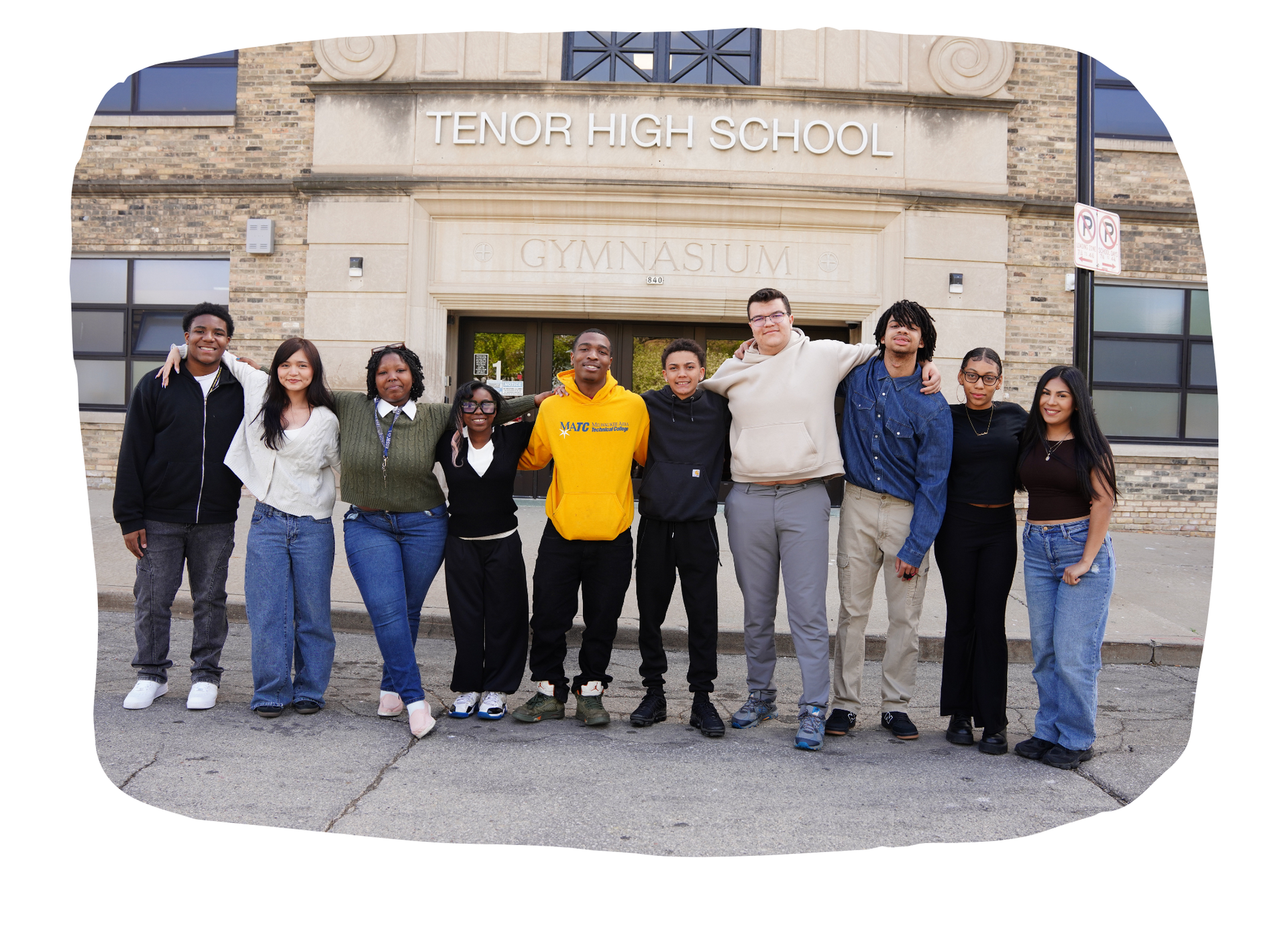 A large group of students posing in front of the school.