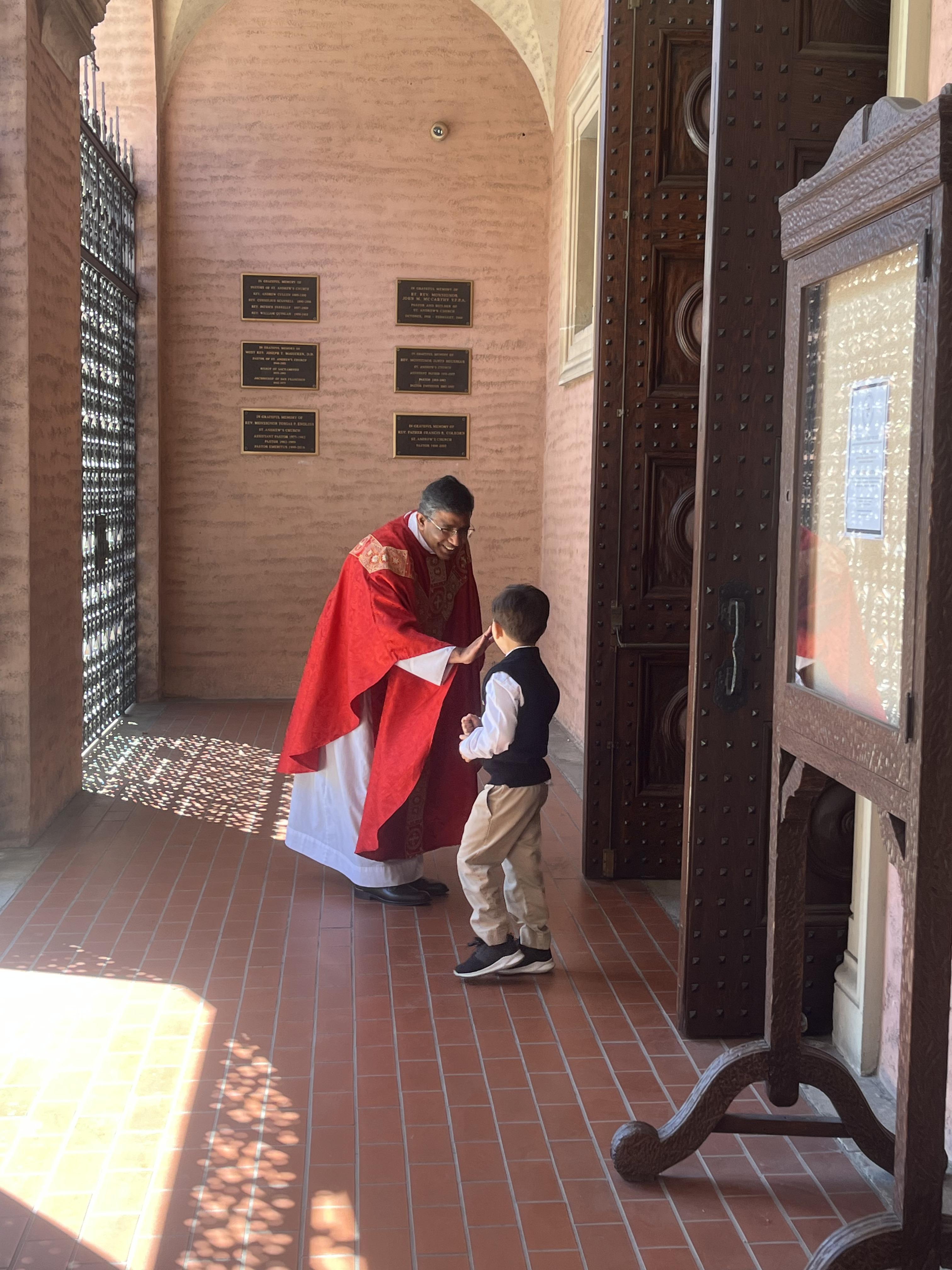 Fr. Sebastian and a student high-fiving after mass