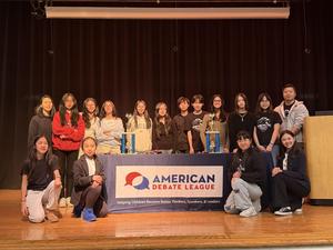 Group of debate students posing on stage for winning at a debate competition.