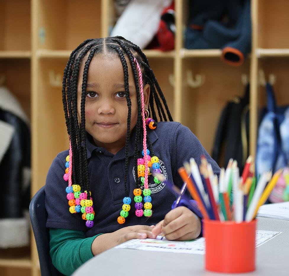 Student writing at a table in a classroom