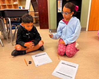 Two children sitting on the floor, engaged with worksheets.