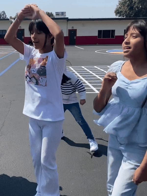 three students dance during break outside on the blacktop