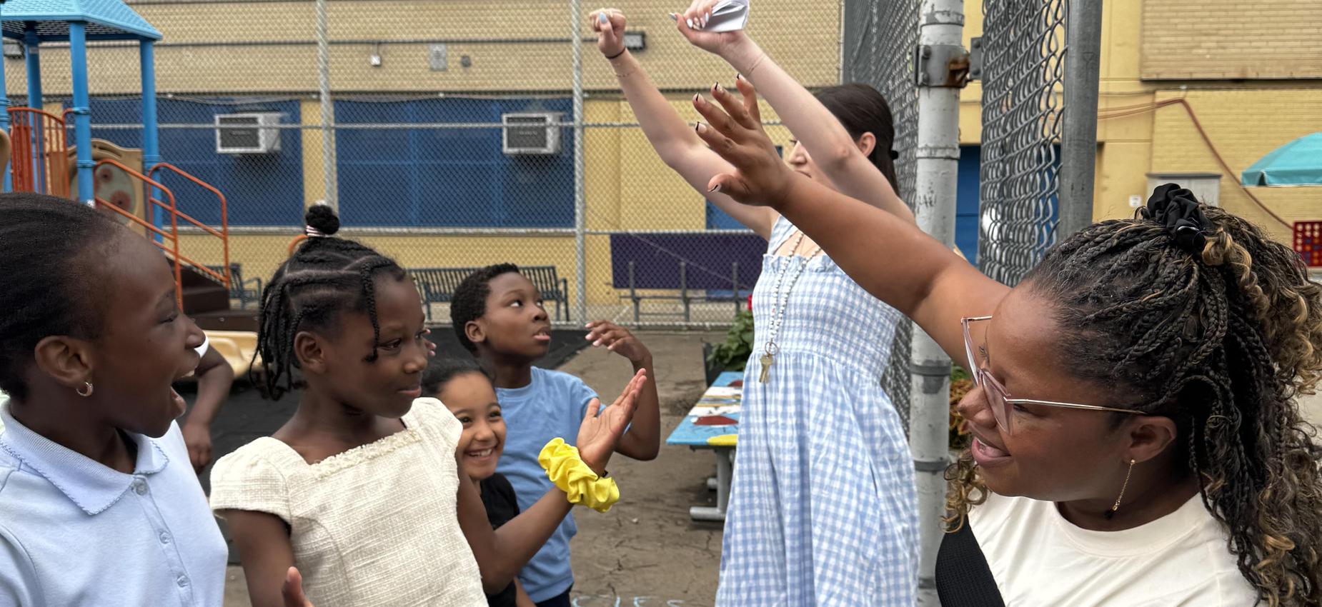 Students interacting with the teacher and the vice principal in the school yard.