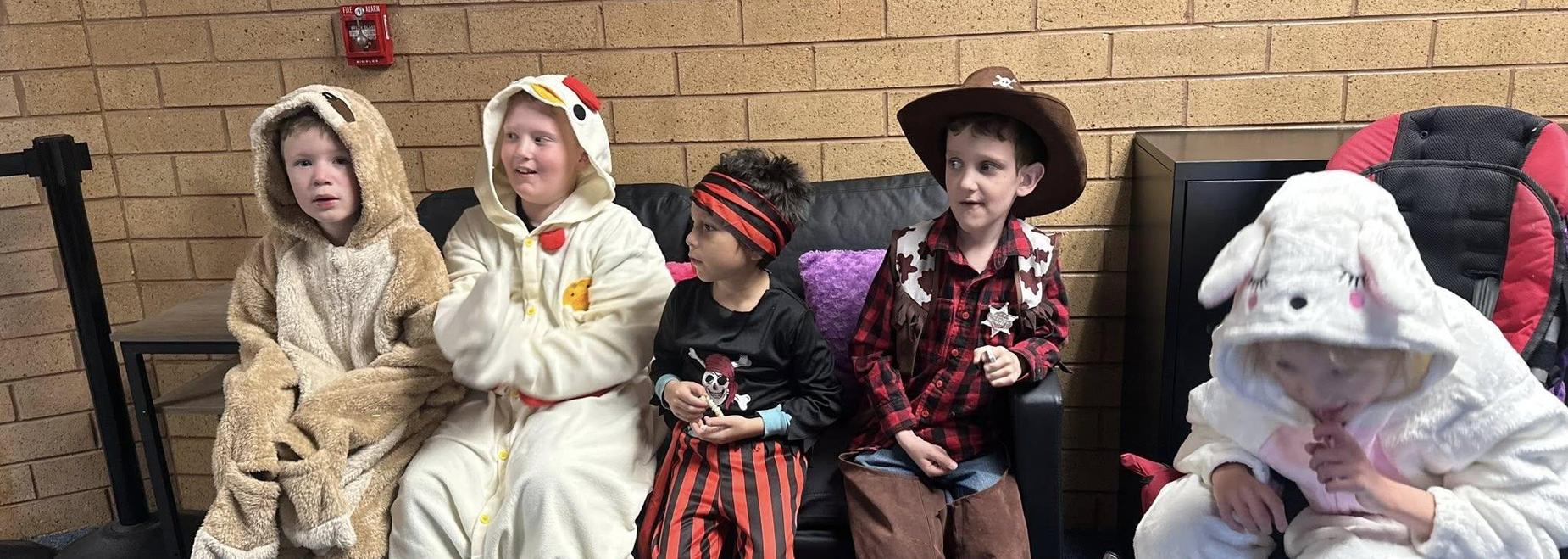 Children in costumes sitting on a couch, including a chicken and a bunny.