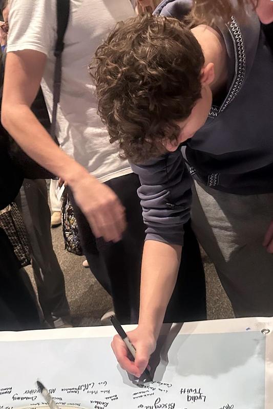 A boy adding his signature to a banner on a table