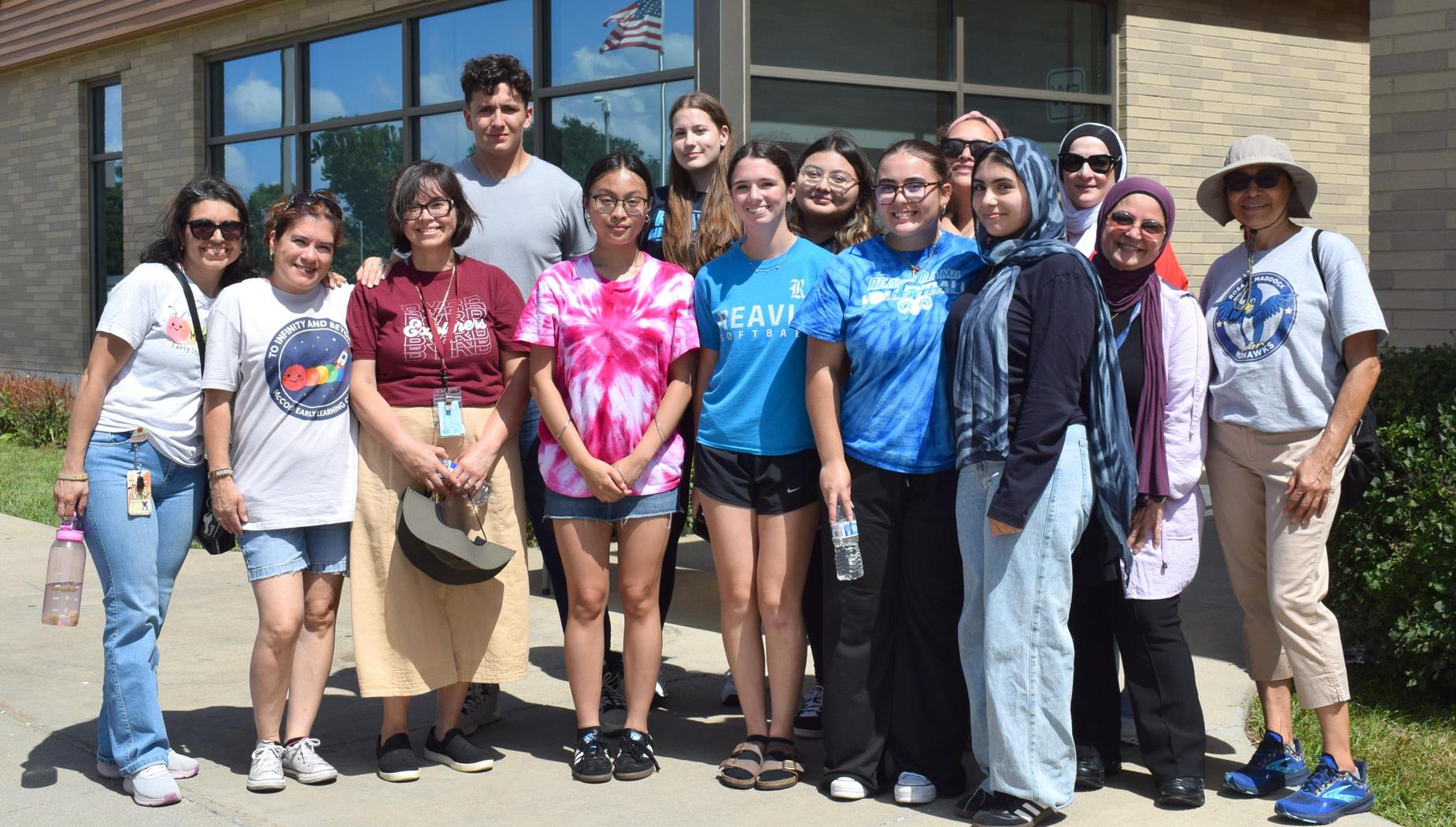 A diverse group of people gathered outside a building, smiling for a photo.