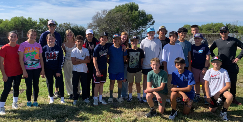 Group of diverse students and adults posing for a photo outdoors on a sunny day.