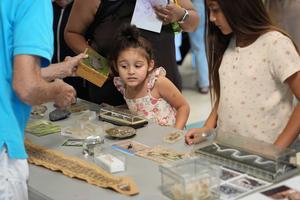 young student with ear close to a box at a science display