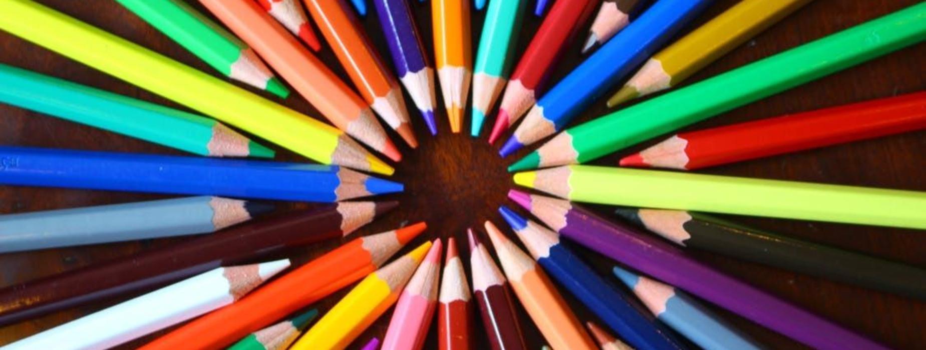 Colorful pencils arranged in a circular pattern on a wooden surface.