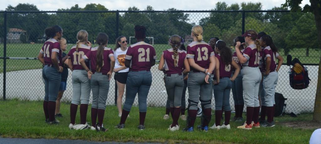 Softball team huddles with coaches
