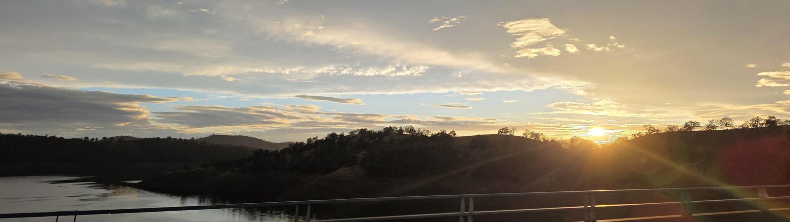 Sunset with a break in cloudy skies on a bridge over the lake