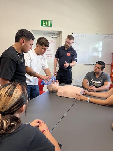 Adults practicing CPR on a dummy during a training session.