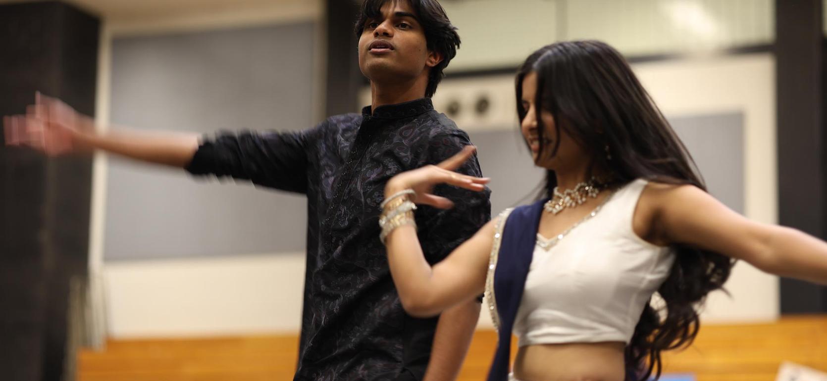 Two dancers performing together, showcasing traditional attire and expressive movements.