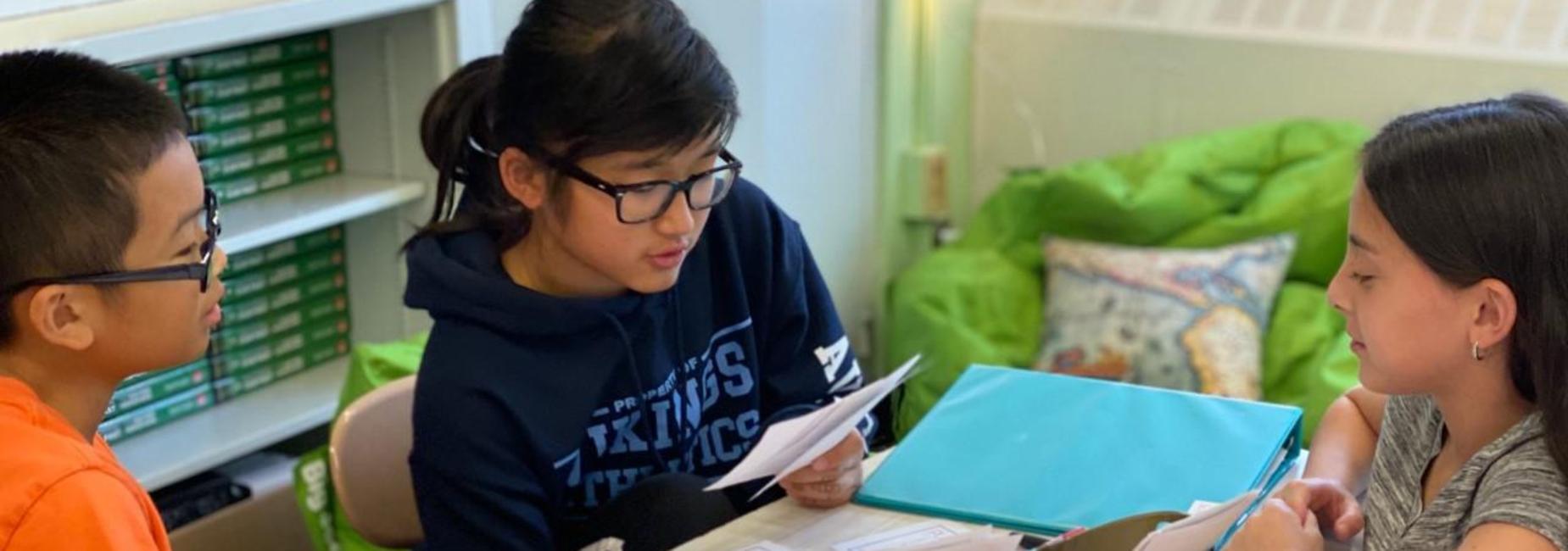 student reading to two other students