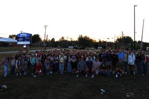 large group of students posing in front of a sunrise